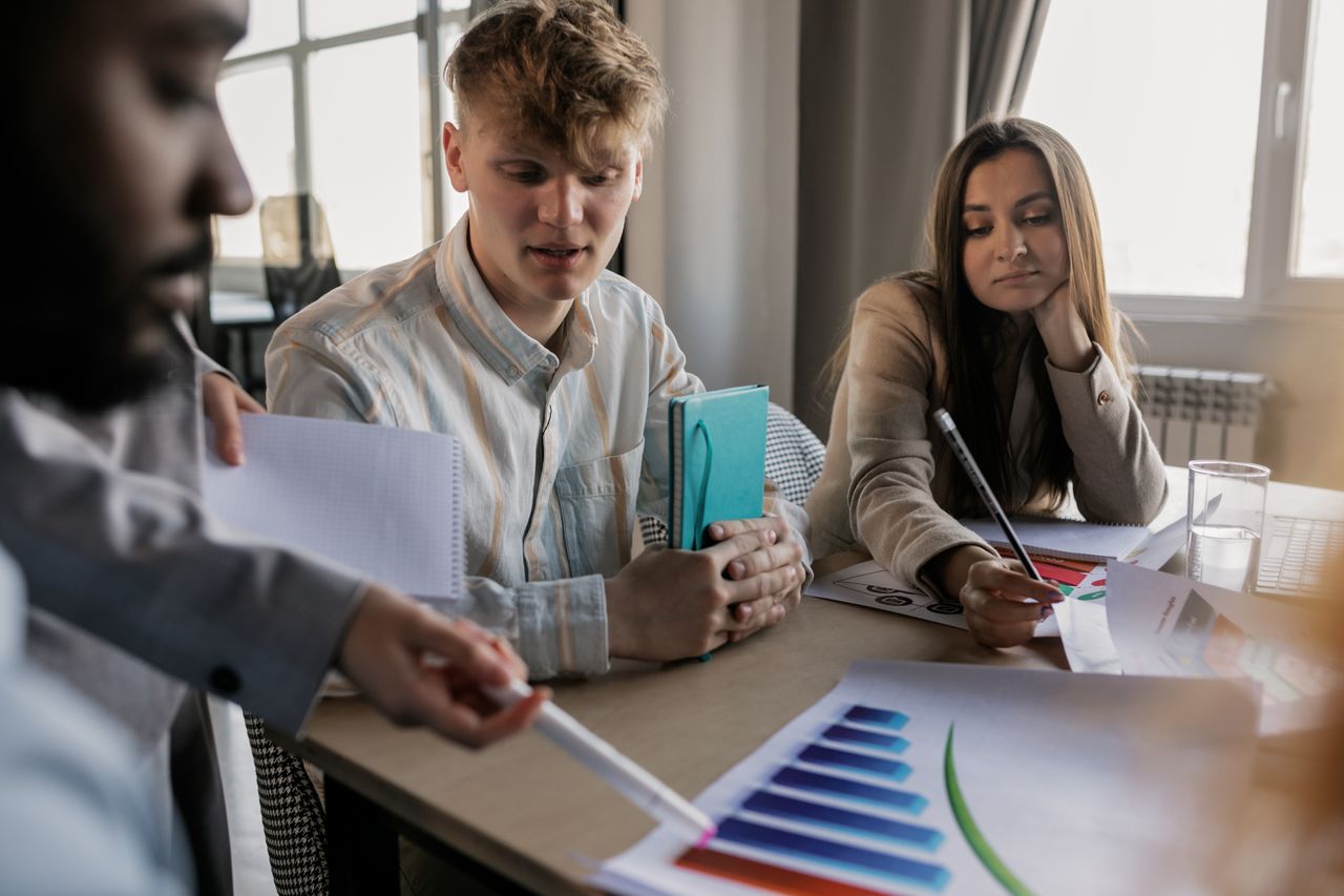 services-02 A diverse team of young professionals engaged in a business meeting analyzing graphs and data.